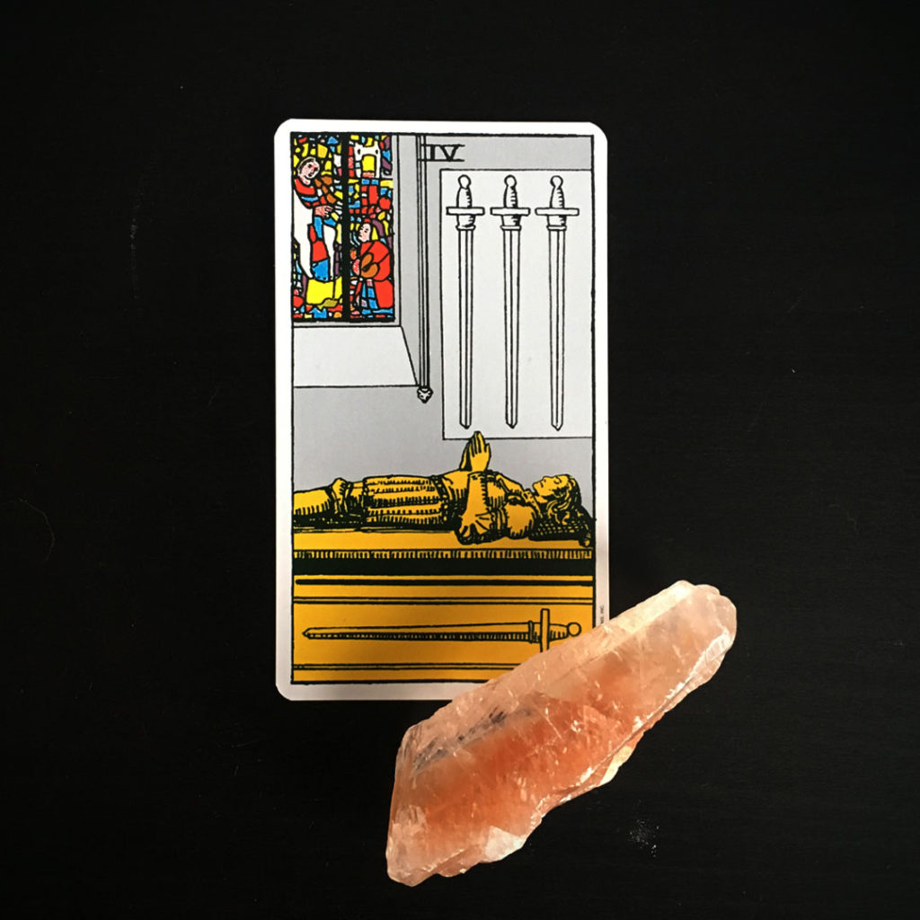 4 of swords tarot card from the rider tarot deck.  crystal is an orange calcite.