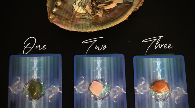 3 piles of tarot cards, each with a different crystal places on top of them. above the cards is an abalone shell with white sage burning. Have you been wondering what the next 6 months will bring? Check out this tarot pick a card reading! Use your intuition and pick the pile you are drawn too.